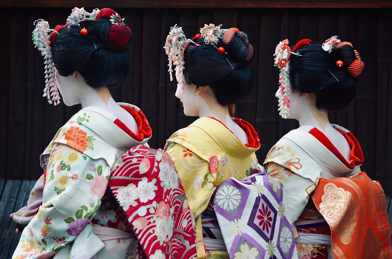 Three geishas in colorful kimonos showcasing traditional Japanese elegance.