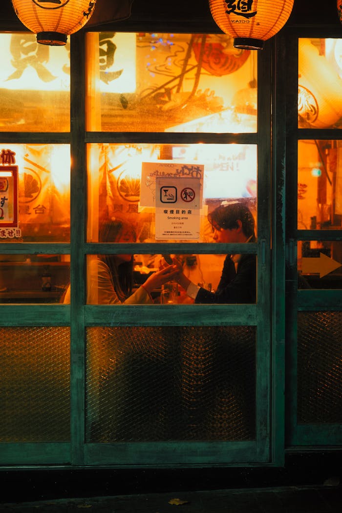 Couple enjoying a warm evening inside a Japanese izakaya with glowing lanterns.